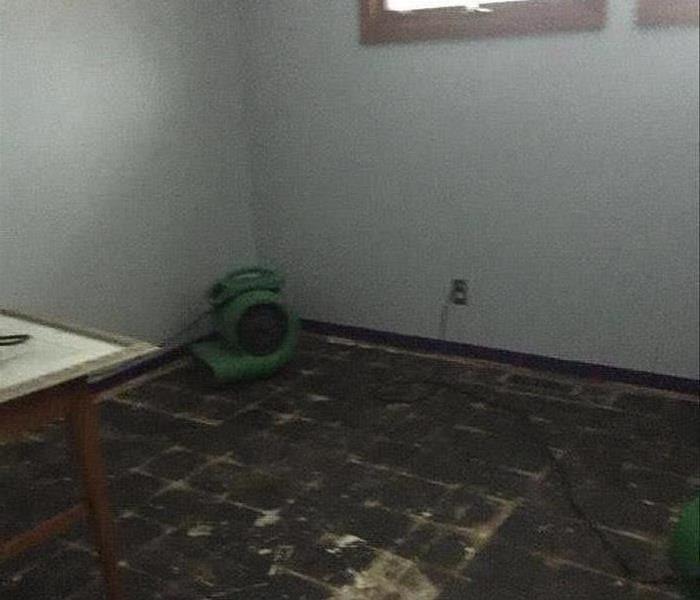 A bedroom flood with carpet ripped up with SERVPRO equipment 
